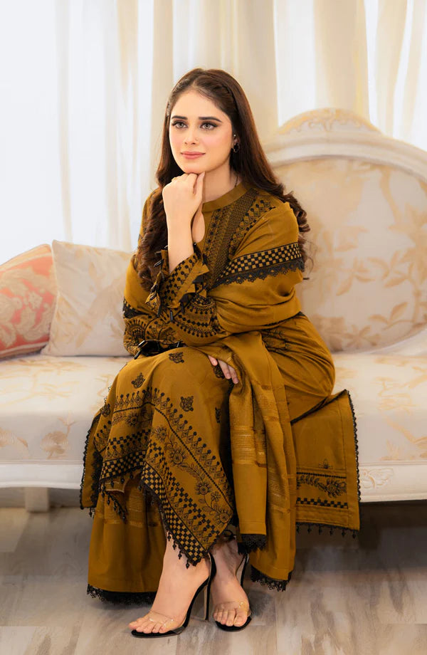 Woman in a mustard yellow traditional outfit sitting on a couch.