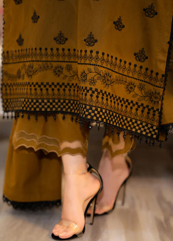 Yellow traditional outfit with black patterns and a sandal on a blurred background